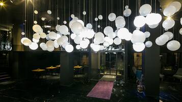 A modern interior with hanging spherical light fixtures, a central seating area, and a marble floor.