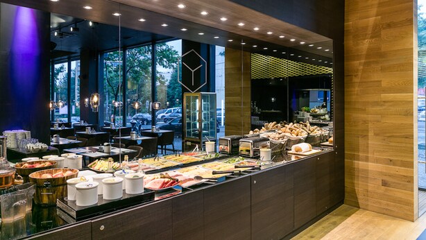 A buffet area with various food options, a seating area, and large windows providing a view of the outdoors. - Pytloun Grand Hotel Imperial (Liberec)