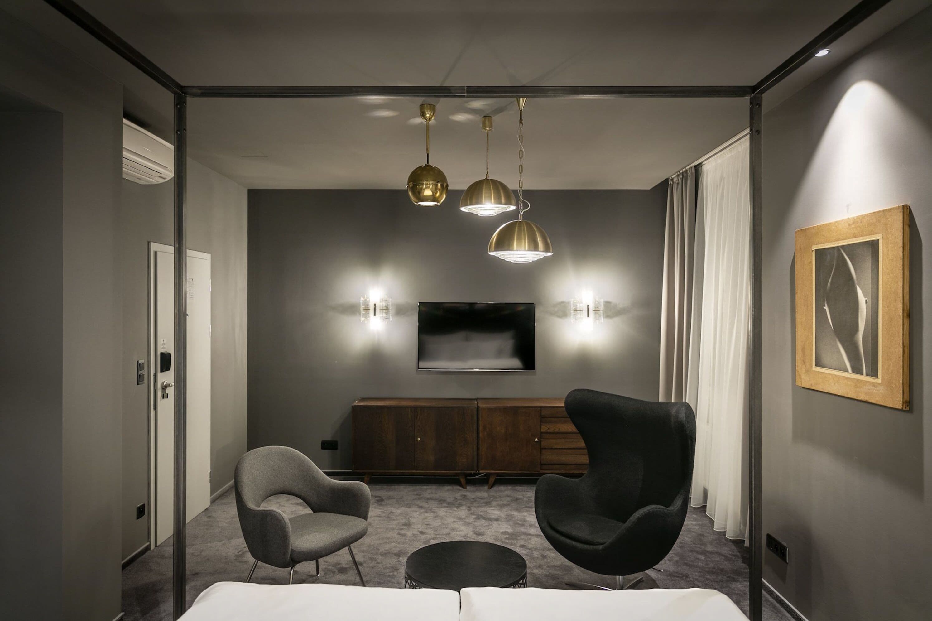 Una sala de estar moderna con un televisor de pantalla plana, dos sillones, una mesa redonda de centro y un mueble de madera.