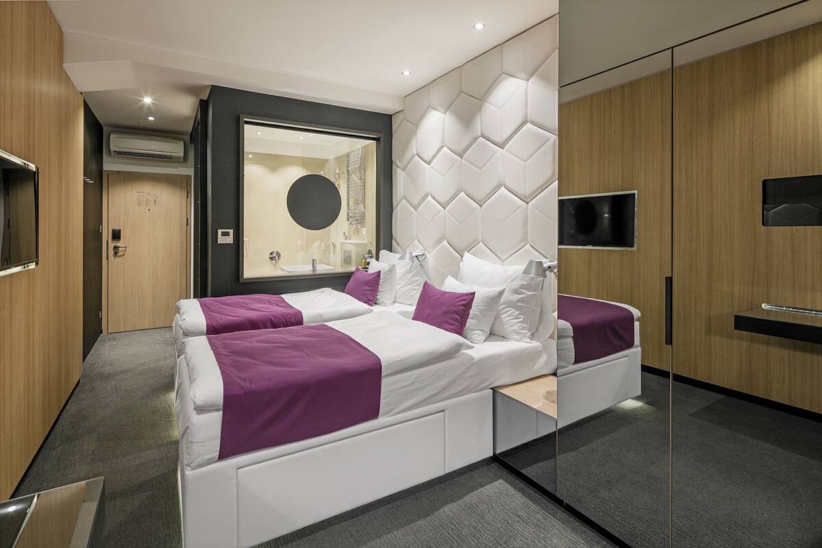 Une chambre moderne avec un grand lit, un téléviseur intégré et un miroir.