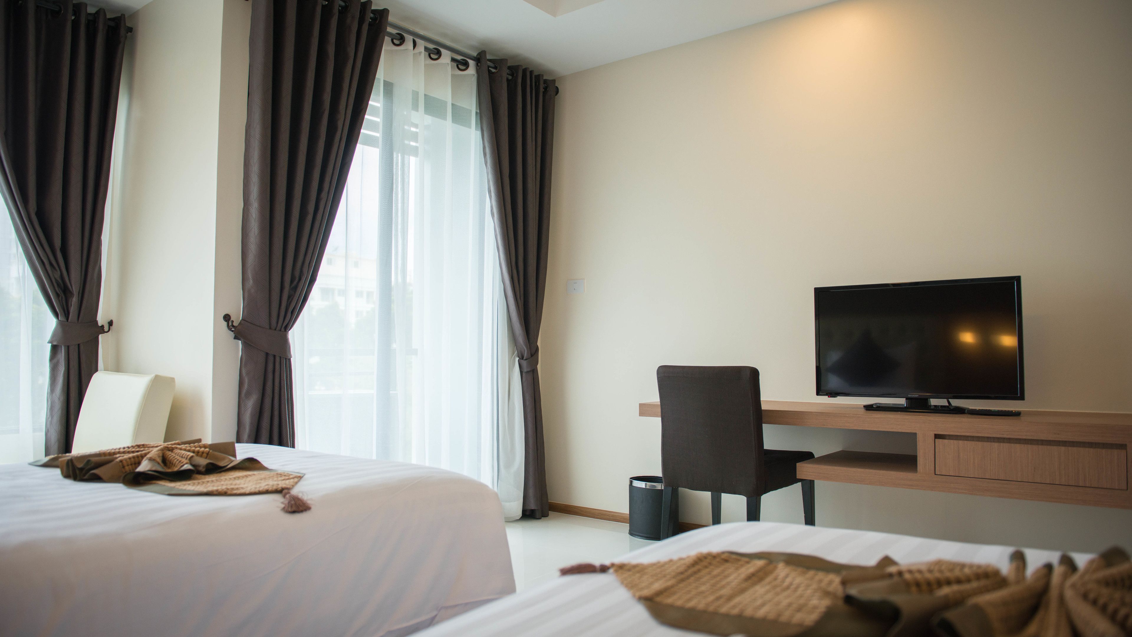 A hotel room with two beds, a TV, a desk, and a chair.