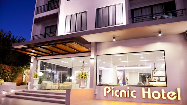 Um hotel moderno com fachada de vidro, área de recepção e escadaria visível que leva à entrada.