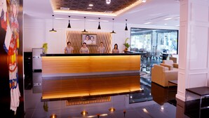 Um hall de hotel moderno com balcão de recepção, área de estar e grandes janelas.