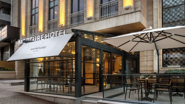 A Mercure Hotel with a glass facade, outdoor seating area, and a modern design. - Mercure Ankara Kızılay (Ankara)