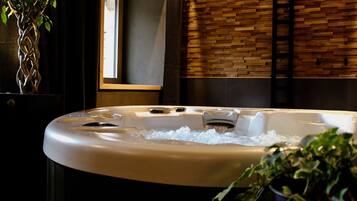 A hot tub with water, a wooden wall, and a window.
