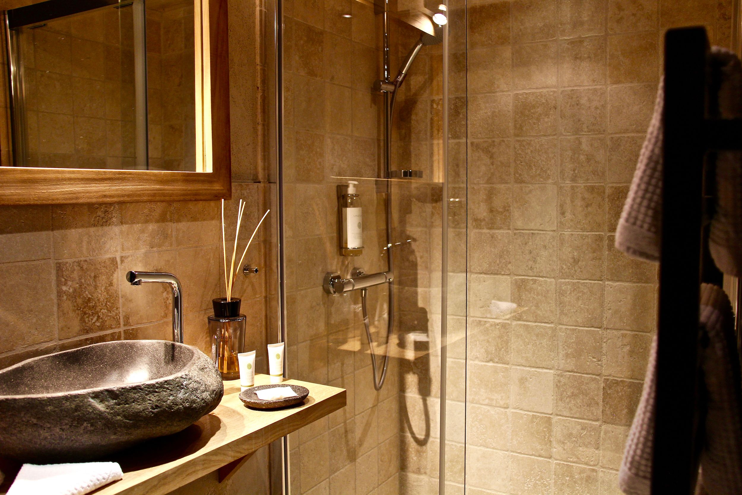 Une salle de bain avec un lavabo en pierre, une douche en verre et un porte-serviettes.