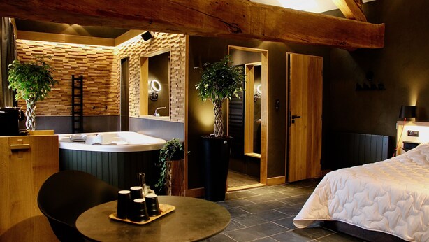 Une salle de bain moderne avec un grand miroir, un lavabo et un espace douche. Le plafond est en bois et il y a une plante dans un coin.