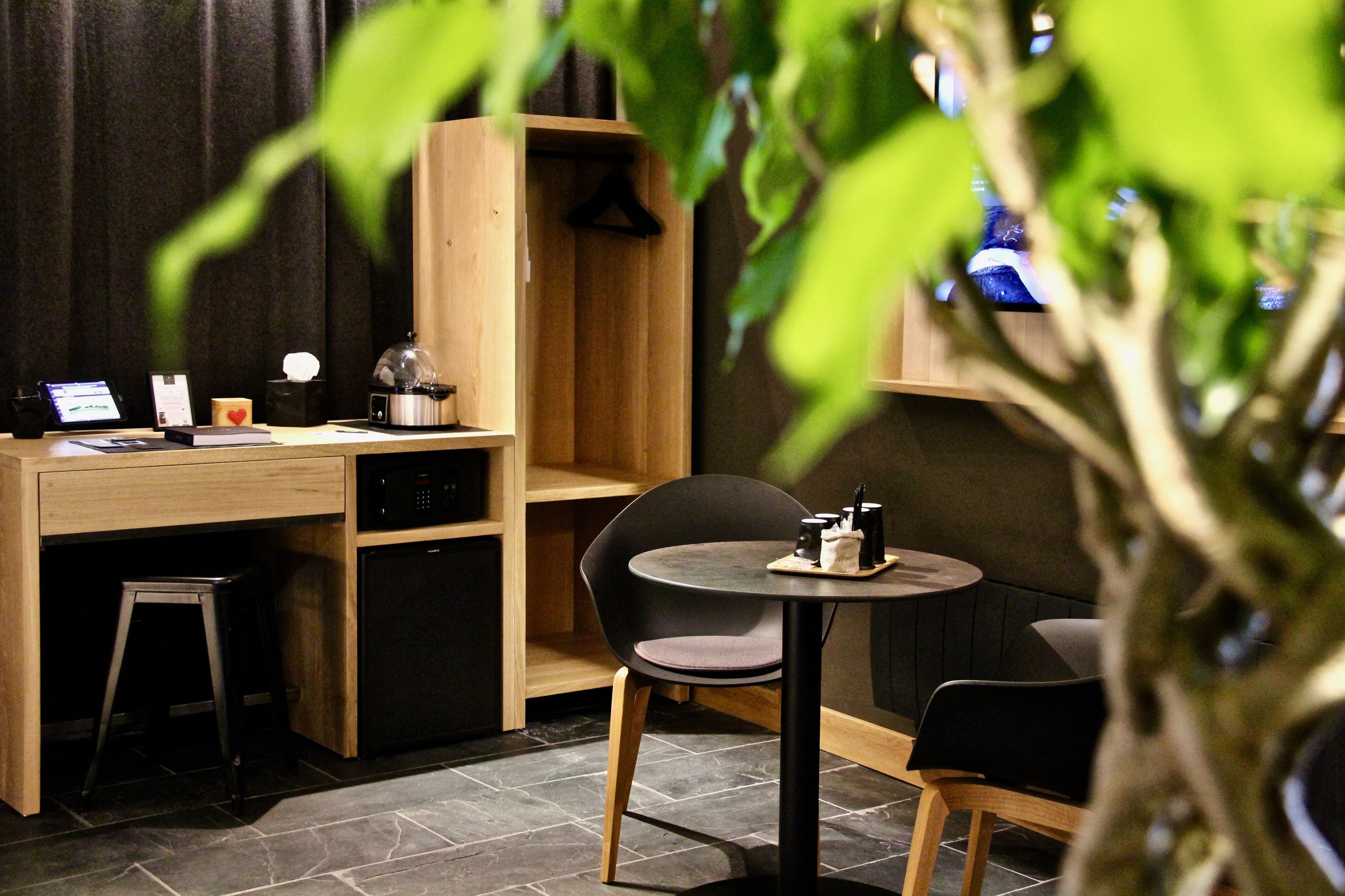 En mysig restaurang med en träinredd bardisk, en liten barhörna och ett runt bord med stolar.