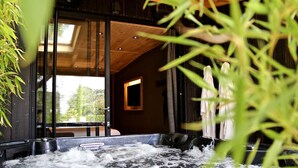 Un bain à remous avec jets d’eau, entouré de plantes d’intérieur et de poutres en bois.