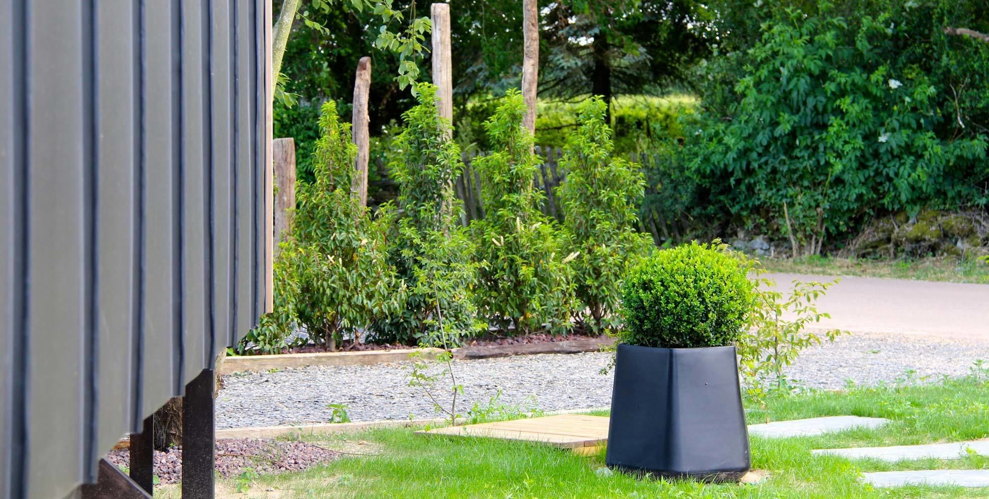 Een tuin met diverse planten en een zwarte plantenbak.