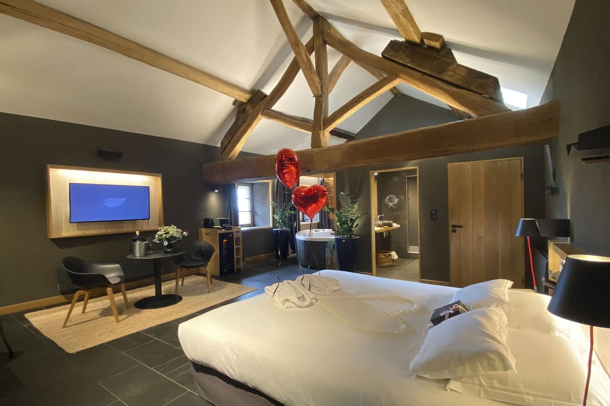Une chambre avec un grand lit, un bureau avec une chaise, une télévision et une fenêtre.