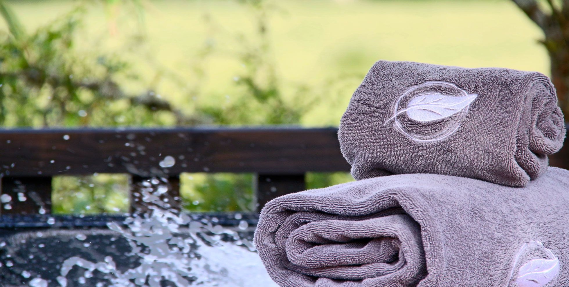 Een handdoek met een bladmotief op een houten bank.