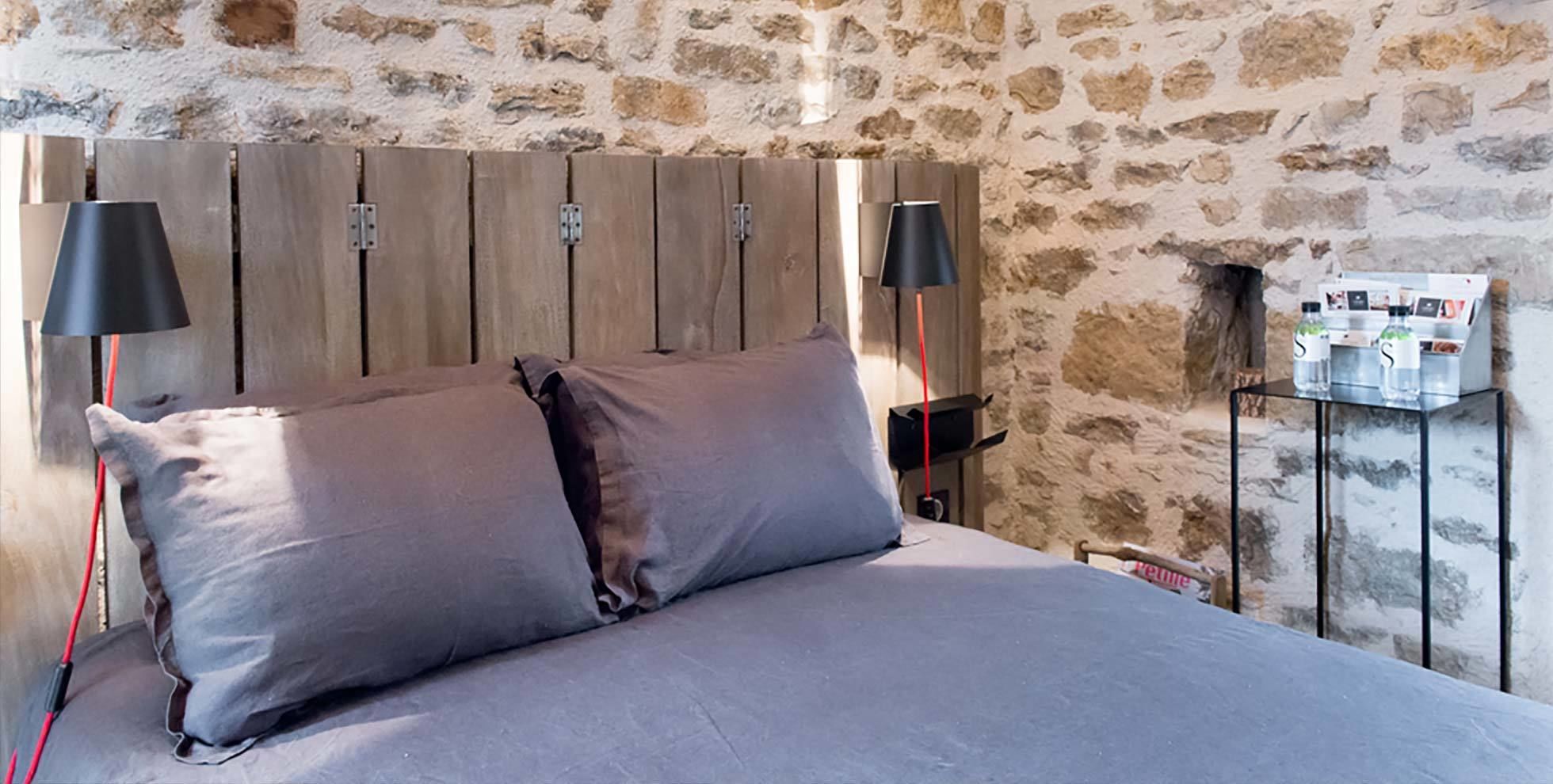 A bed with two pillows, a wooden headboard, and two bedside lamps.