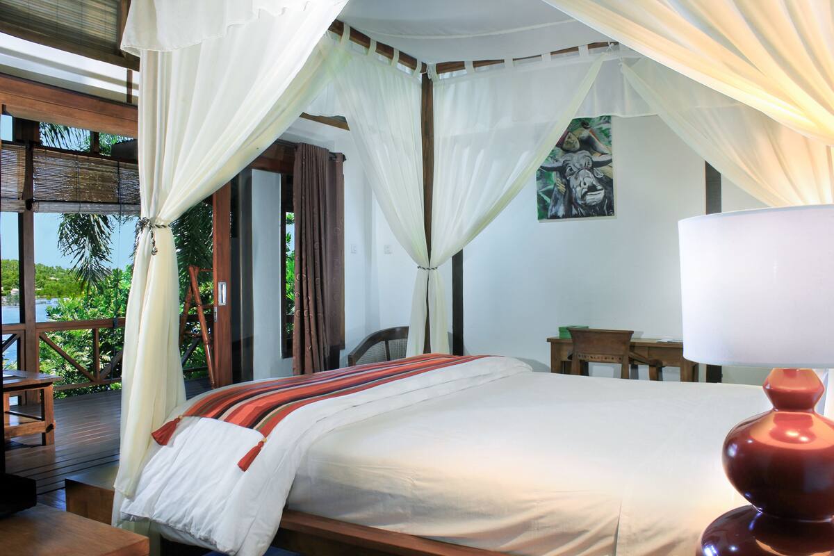 A bedroom with a bed, a nightstand, a lamp, and a painting on the wall.
