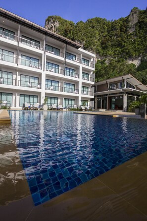 Una piscina al aire libre, sillones reclinables de piscina