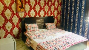 A bedroom with a bed, a headboard, a wall-mounted air conditioner, and patterned wallpaper. - Magmercy Apartments (Lagos)
