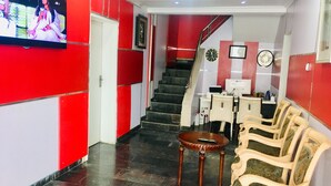 A reception area with a TV, red and white walls, a staircase, and a seating area with chairs and a table. - Magmercy Apartments (Lagos)