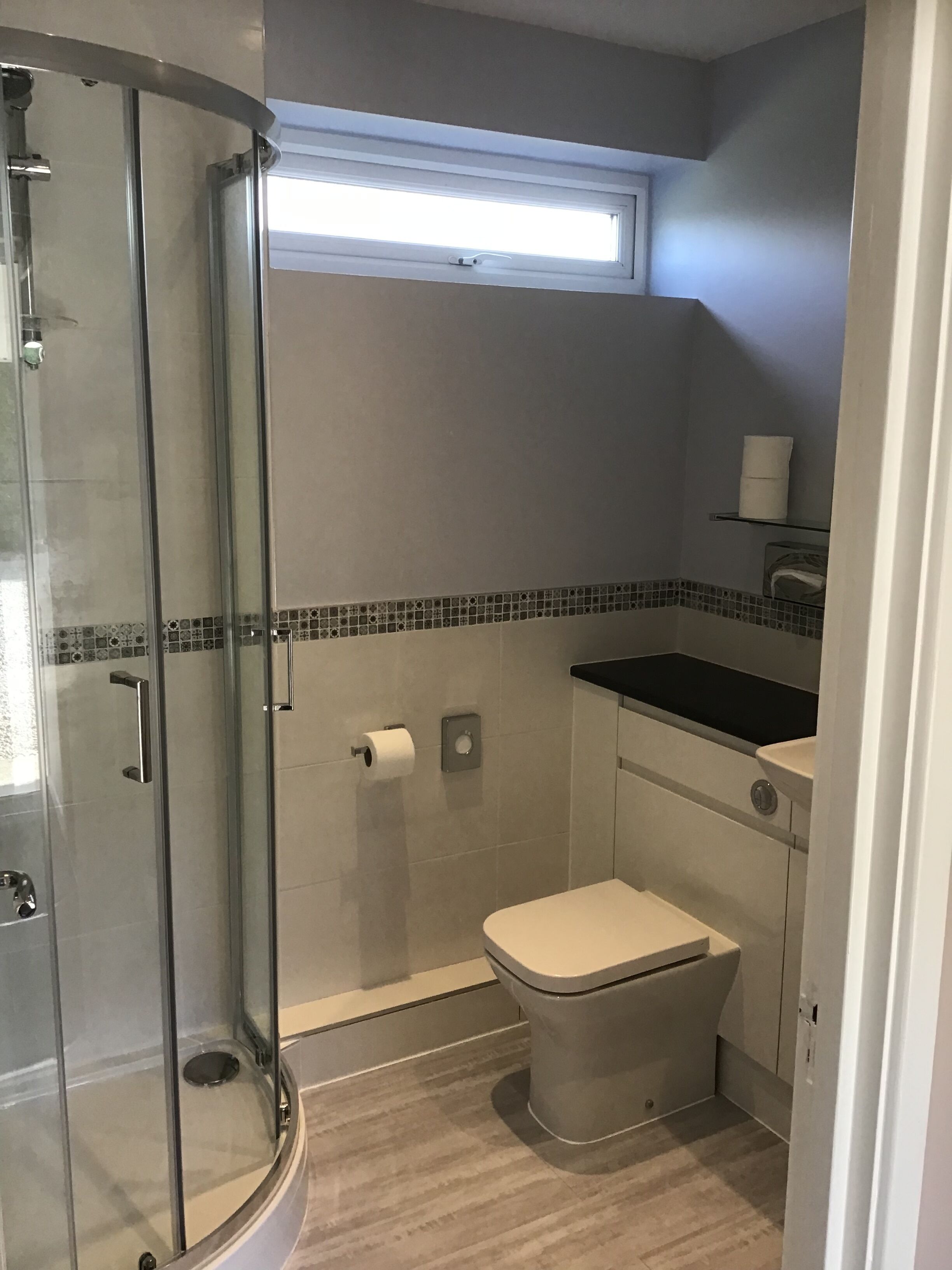 A compact bathroom with a glass shower enclosure, a toilet, and a sink.