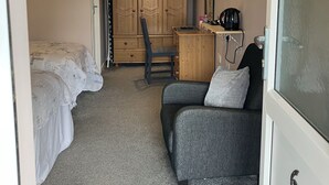 A compact room with a bed, a desk, a chair, a television, and a wardrobe. - The New Inn Motel (York)