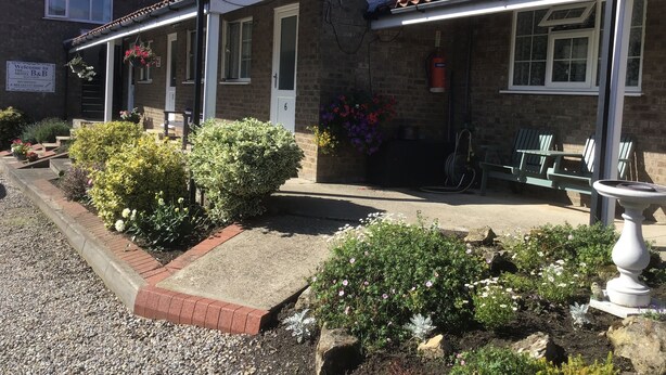 A brick building with a tiled roof, a reception area, and outdoor seating. - The New Inn Motel (York)
