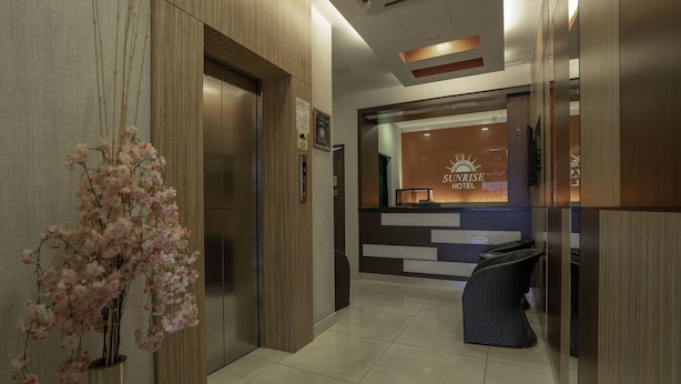 A reception area with a reception desk, a sign for the Sunrise Hotel, and a corridor leading to elevators. - Sunrise Hotel (Petaling Jaya)