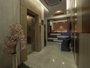 A reception area with a reception desk, a sign for the Sunrise Hotel, and a corridor leading to elevators. - Sunrise Hotel (Petaling Jaya)