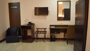 A small, compact room with a desk, chair, wardrobe, and a mirror. - Sunrise Hotel (Petaling Jaya)