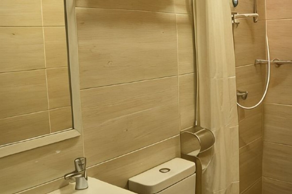Une salle de bain comprenant des toilettes, un espace douche et un miroir.