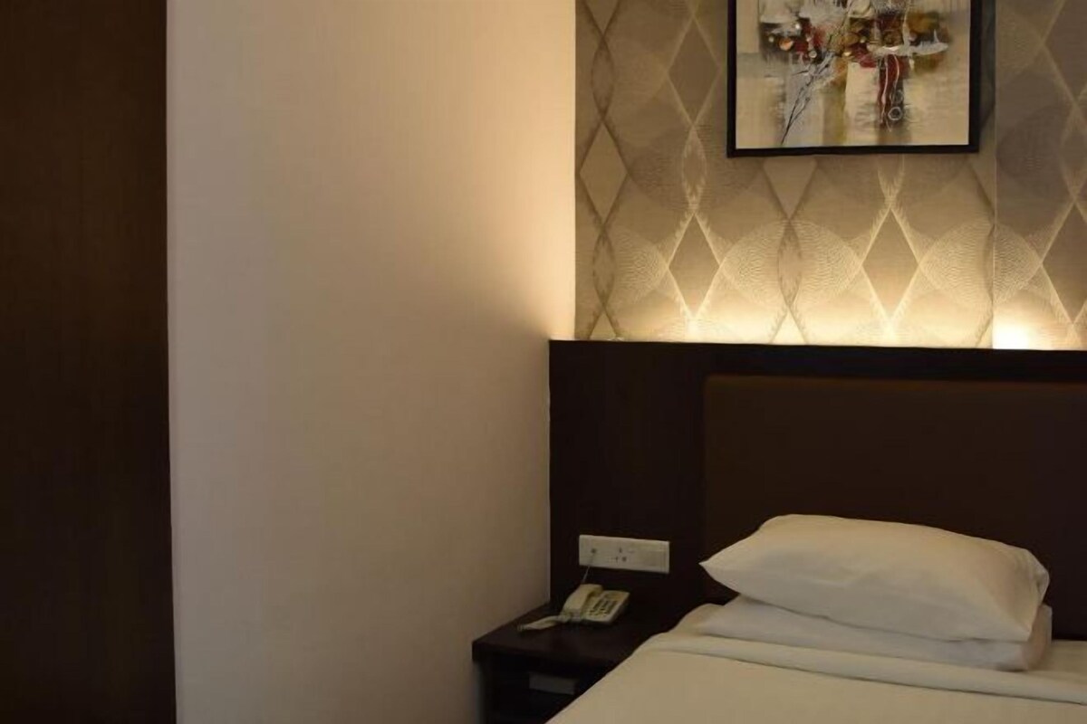 Una habitación de hotel con una cama, una mesita de noche con un teléfono y una obra de arte colgada en la pared.