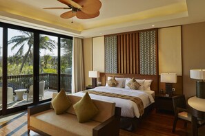 A hotel room with a large bed, two bedside tables with lamps, a sofa, and a balcony with outdoor furniture. - Bali National Golf Villas (Nusa Dua)