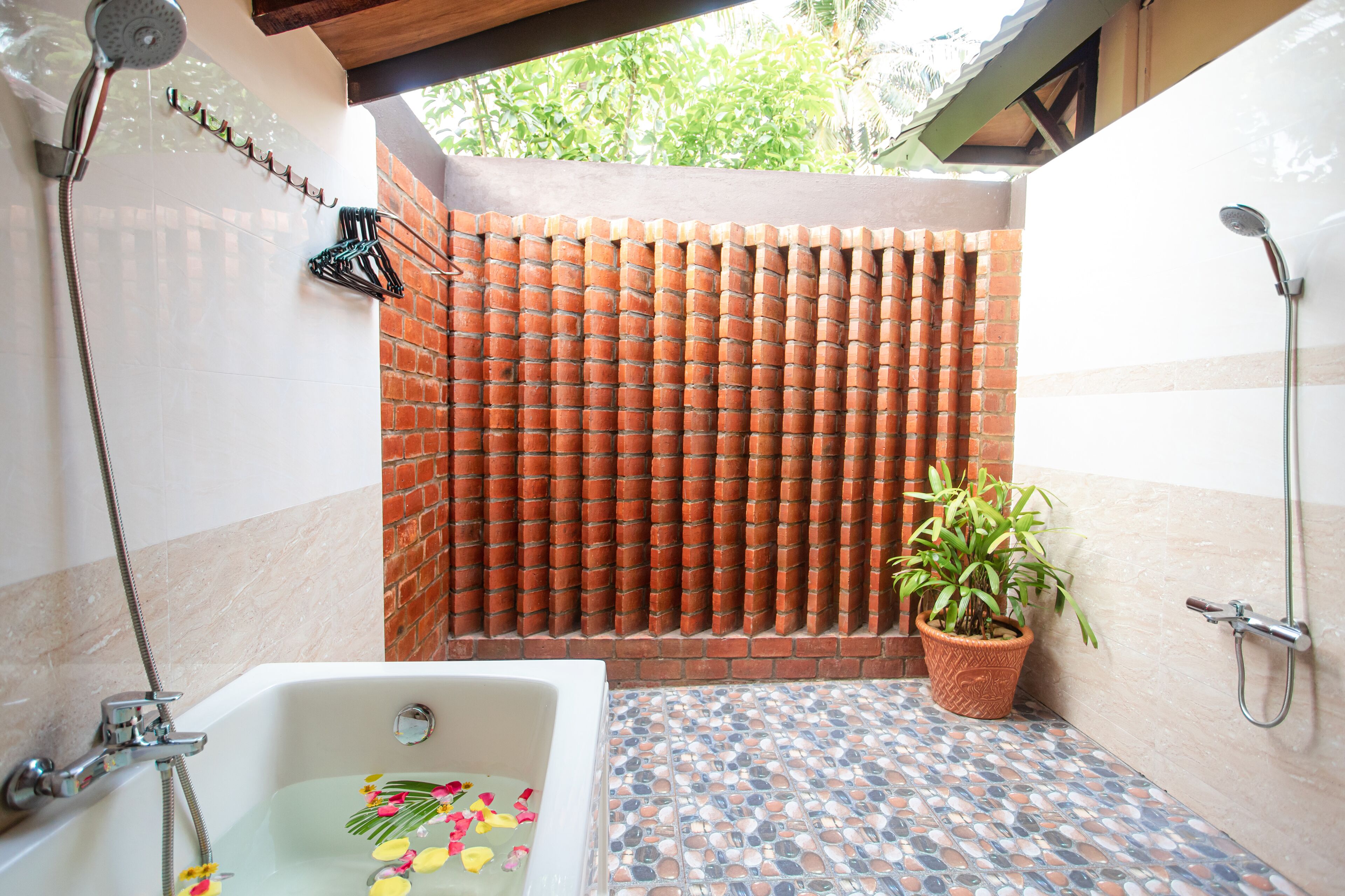 Casa de banho com soalho em mosaico, chuveiro, banheira e planta num vaso.