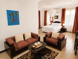 A hotel room with a bed, two sofas, a coffee table, and a painting on the wall.