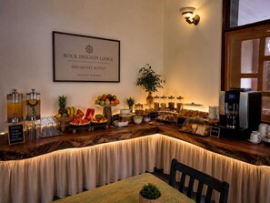 A breakfast buffet setup with various fruits, juices, and bread at Rock Heights Lodge.
