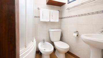 Une salle de bain équipée de toilettes, d’un bidet et d’un lavabo.