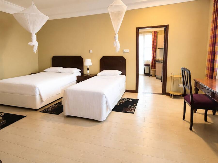 Habitación de hotel con dos camas, un escritorio, una silla y una mesa de comedor.