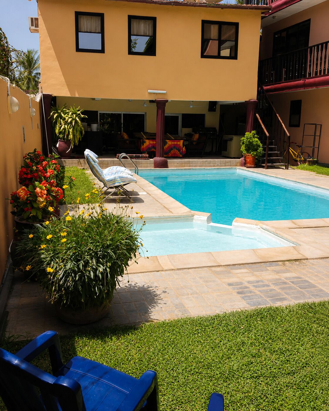 A swimming pool with a patio area, a covered seating area, and a staircase leading to an upper level.