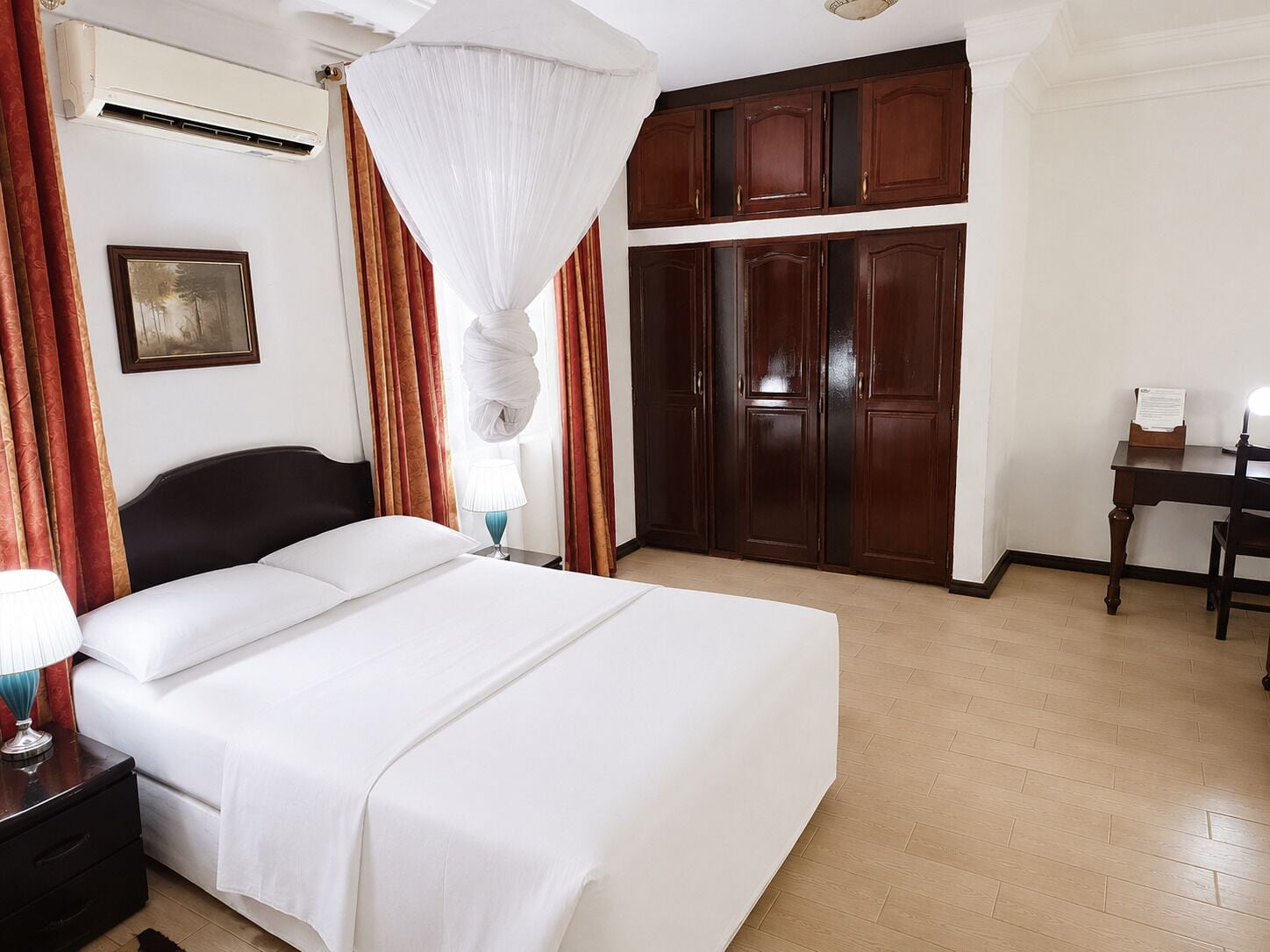 A hotel room with a bed, a desk, and a wardrobe.