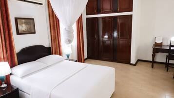 A hotel room with a bed, a desk, and a wardrobe.