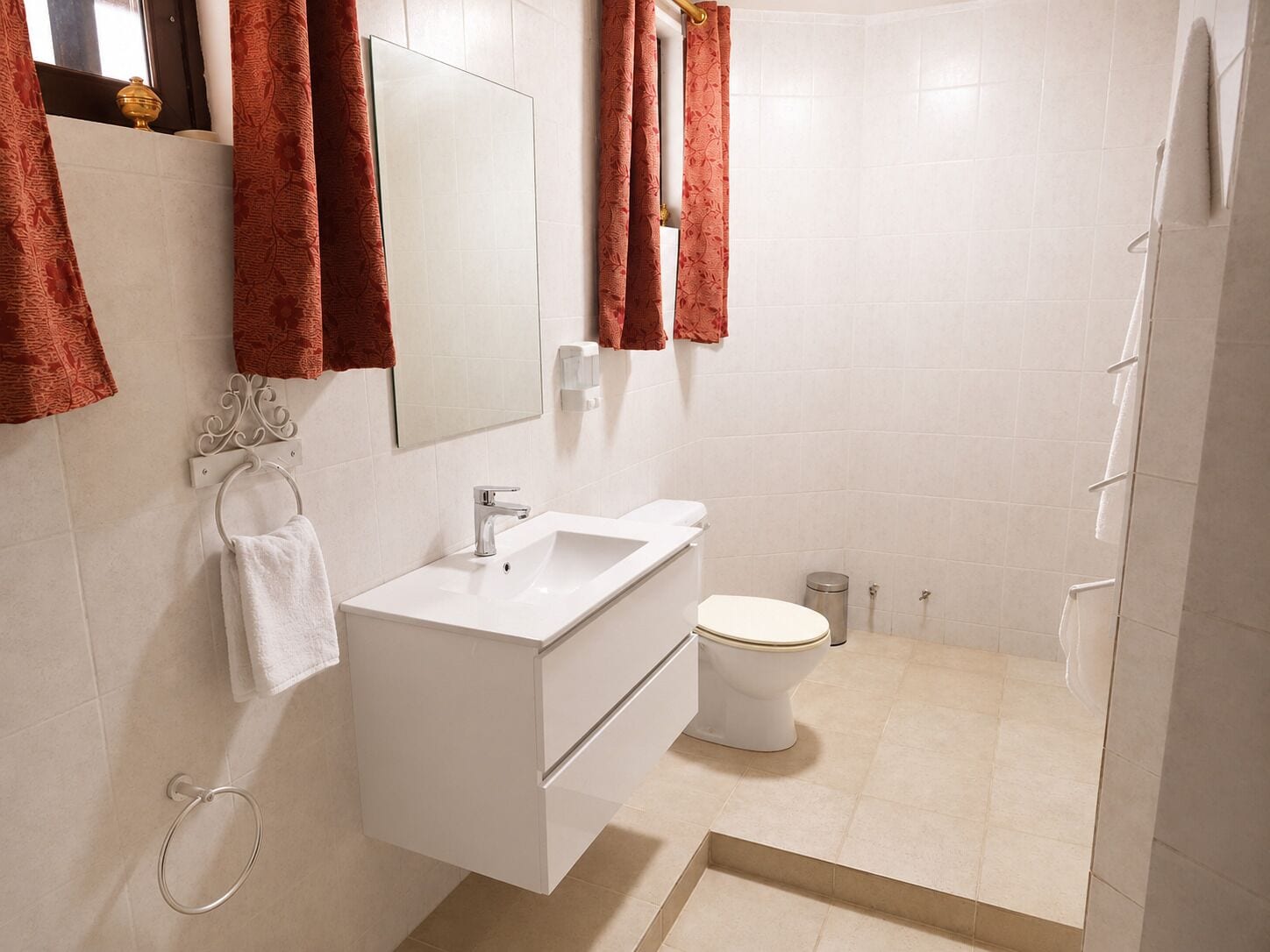 A modern bathroom with a white sink, mirror, and toilet.