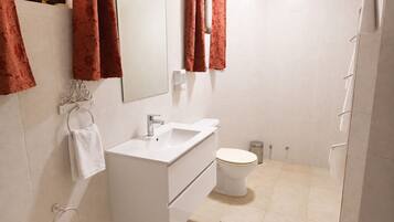 A modern bathroom with a white sink, mirror, and toilet.