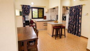 A compact kitchen with a dining area, a water dispenser, and a refrigerator.