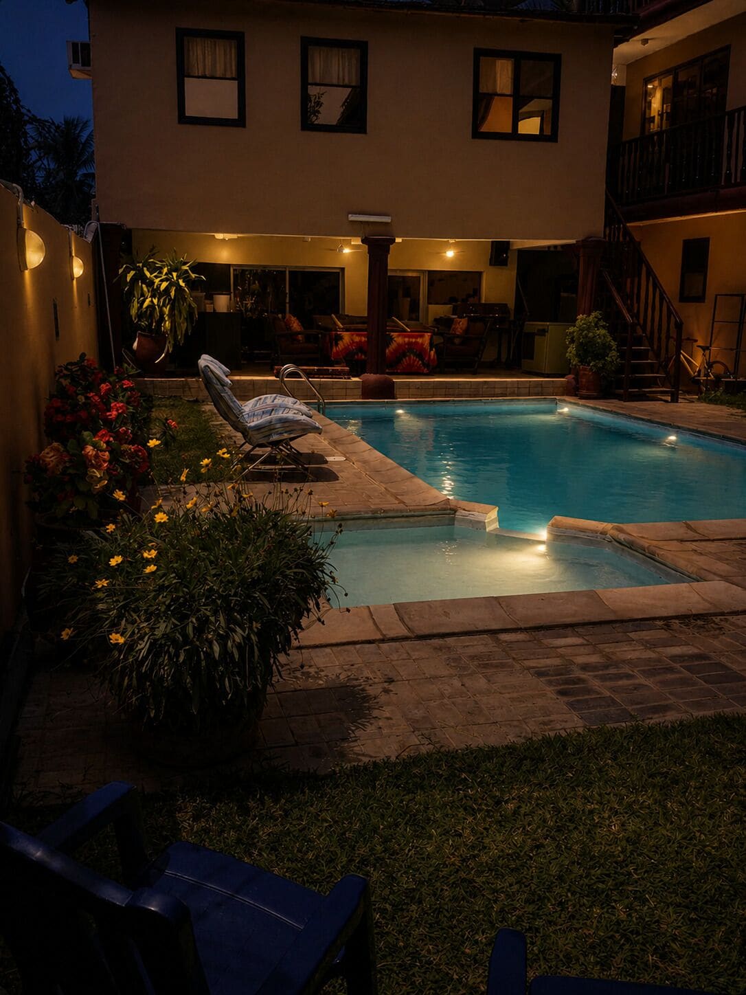 A swimming pool with a sunken hot tub, surrounded by a patio area with outdoor furniture and potted plants.