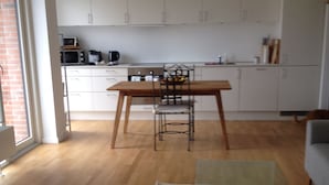 Una cocina moderna con armarios blancos, una mesa de comedor de madera y una mesa de centro de vidrio.