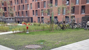 Un patio con una tapa de registro, un hidrante rojo y una zona de estacionamiento para bicicletas.