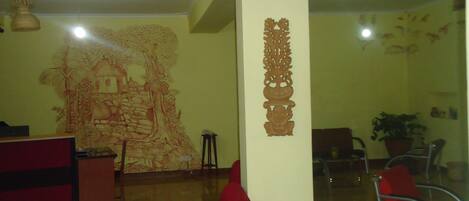 Un vestíbulo amplio con un sofá rojo, un mural decorativo y un mostrador de recepción.