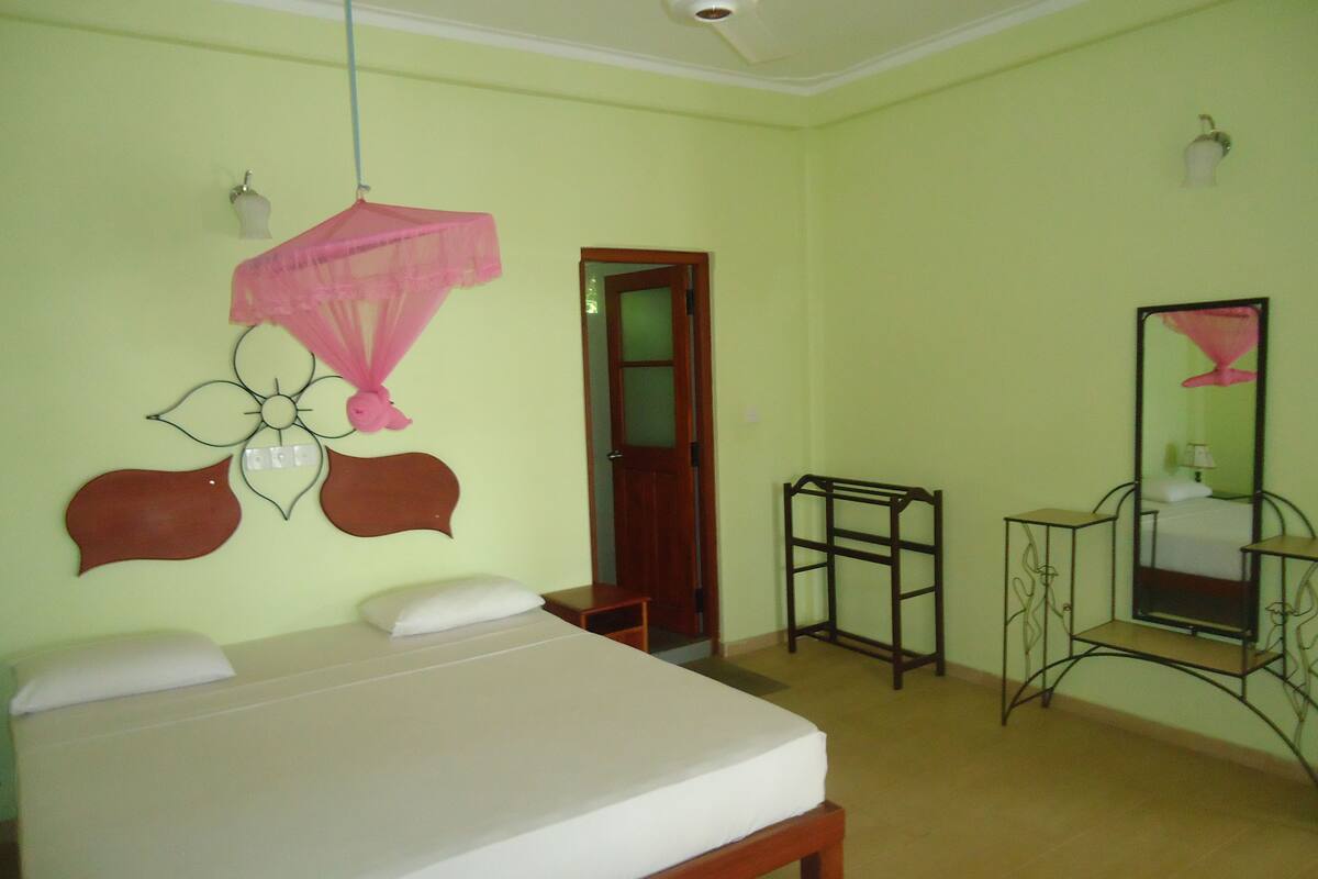 Un dormitorio con cama, mesita de noche, espejo y mosquitero colgado.