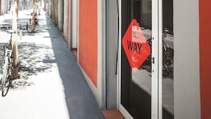 Un bâtiment à la façade rouge, avec un panneau indiquant la direction et un vélo garé devant.