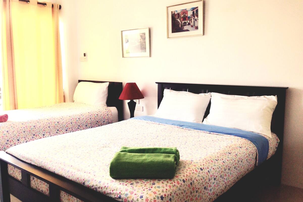 A hotel room with two beds, a red lamp, and a framed picture on the wall.