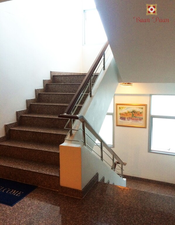 A staircase with a handrail, a welcome mat, and a framed picture on the wall. - Baan Paan Hua Hin (Hua Hin)