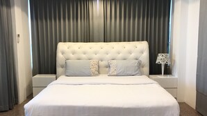 A neatly arranged bedroom with a tufted headboard, two nightstands, and a bed with white bedding. - Baan Paan Hua Hin (Hua Hin)